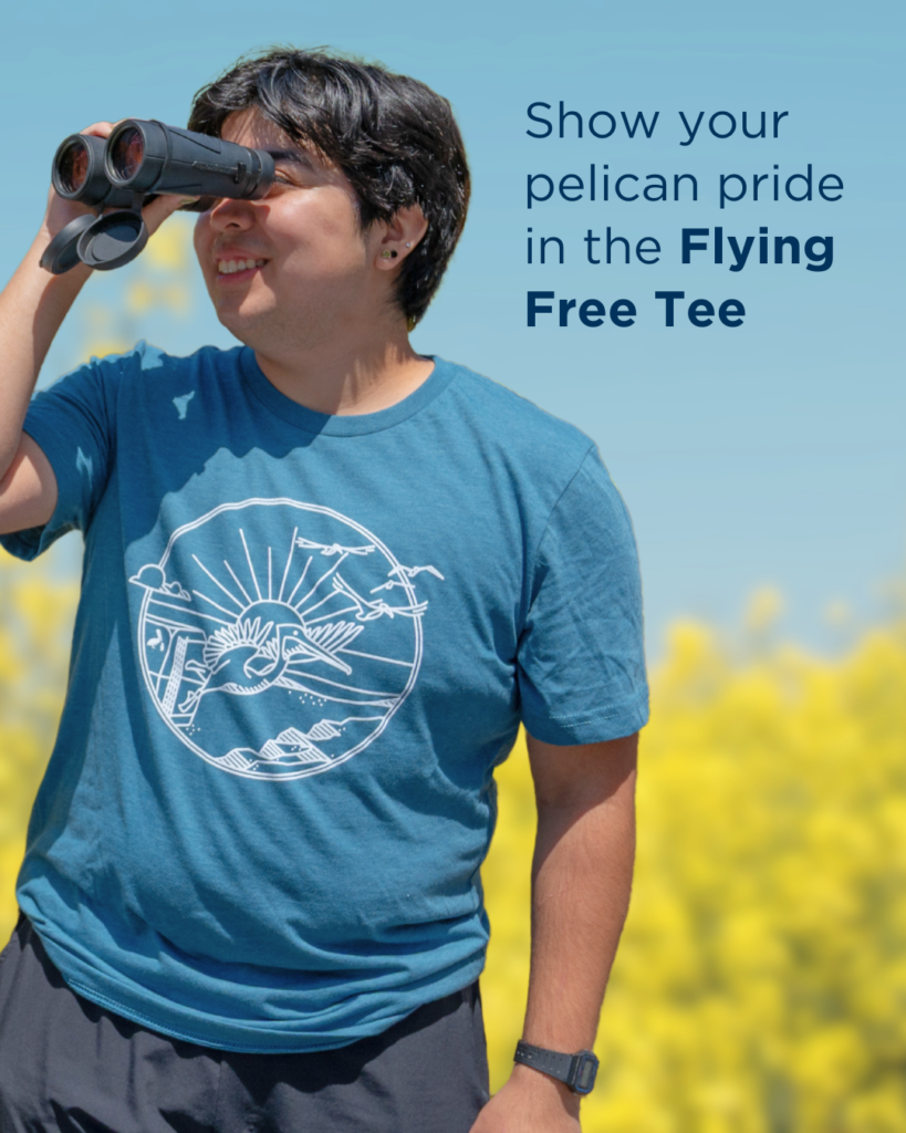 Chris looks out with binoculars while wearing teal Flying Free tee